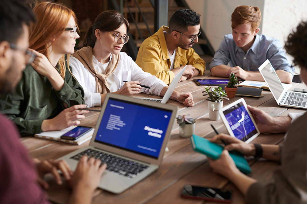 Group of people at a table in an office with a laptop