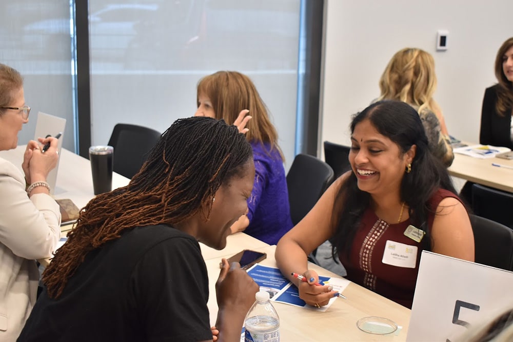 Two women laughing together at 2023 Women INfluencing Business Morning Mixer