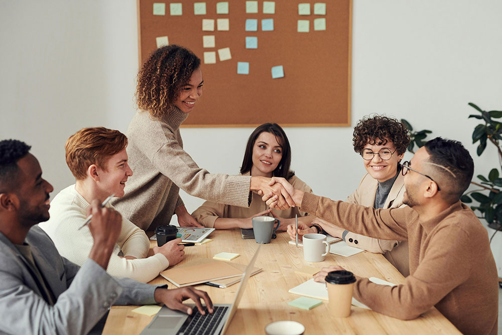 People around a conference table shaking hands